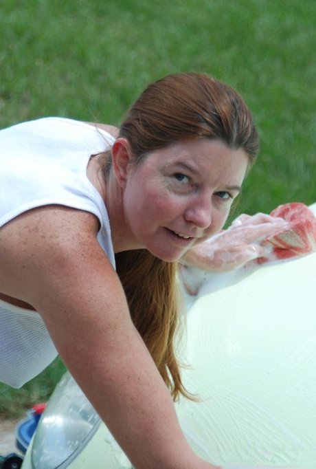 Mature redhead Dee Delmar wets her big tits and twat with hose on concrete pad 69240367