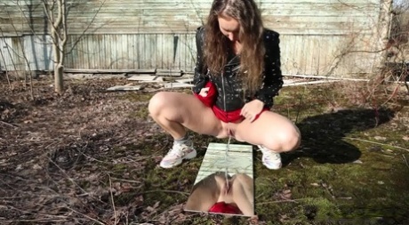 Brunette girl Nikky B takes a piss over a mirror behind a rustic dwelling 21767466